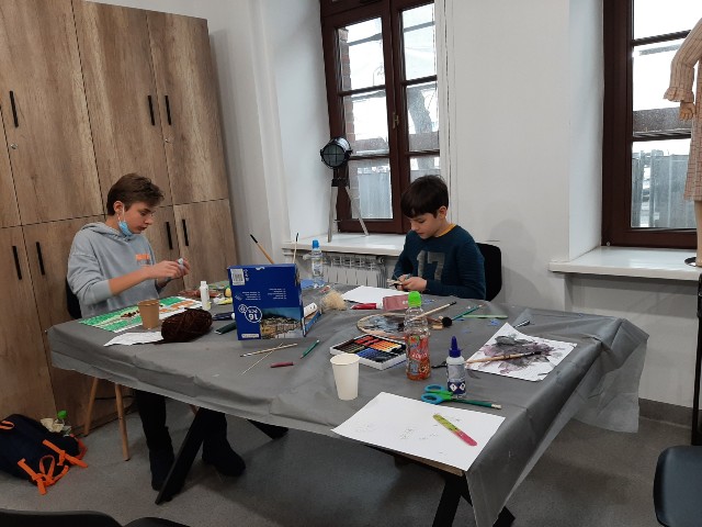 Dwóch chłopców maluje farbami siedząc przy stole